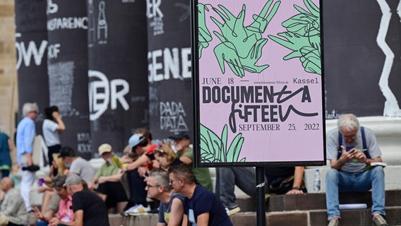 Des visiteurs de la documenta fifteen sont assis sur les marches du Fridericianum. © picture alliance Photo : Uwe Zucchi