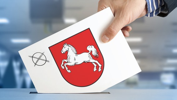 Une carte électorale avec une croix et les armoiries de la Basse-Saxe est déposée dans une urne électorale. © fotolia.com Photo : _AndreL
