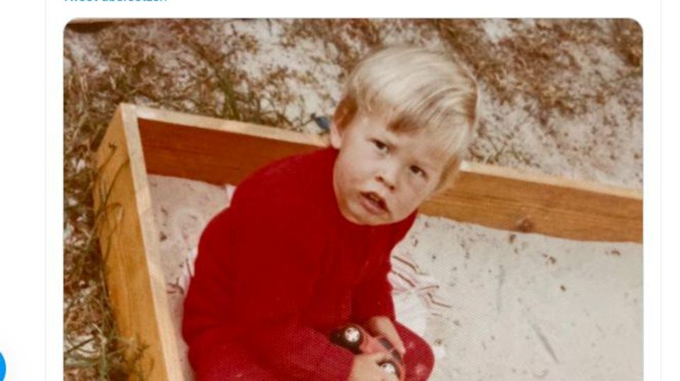 Elon Musk assis dans un bac à sable comme un petit garçon blond de trois ans